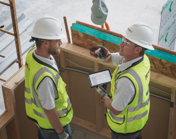 Construction workers standing over architectural plans
