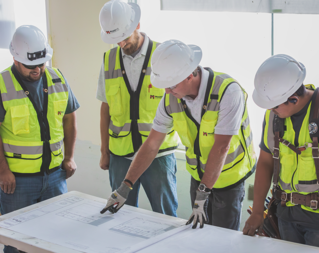 Construction workers standing over architectural plans