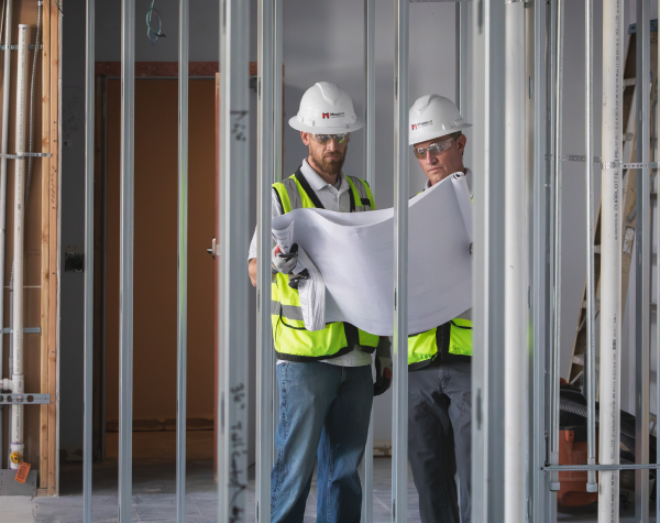 Construction workers standing over architectural plans